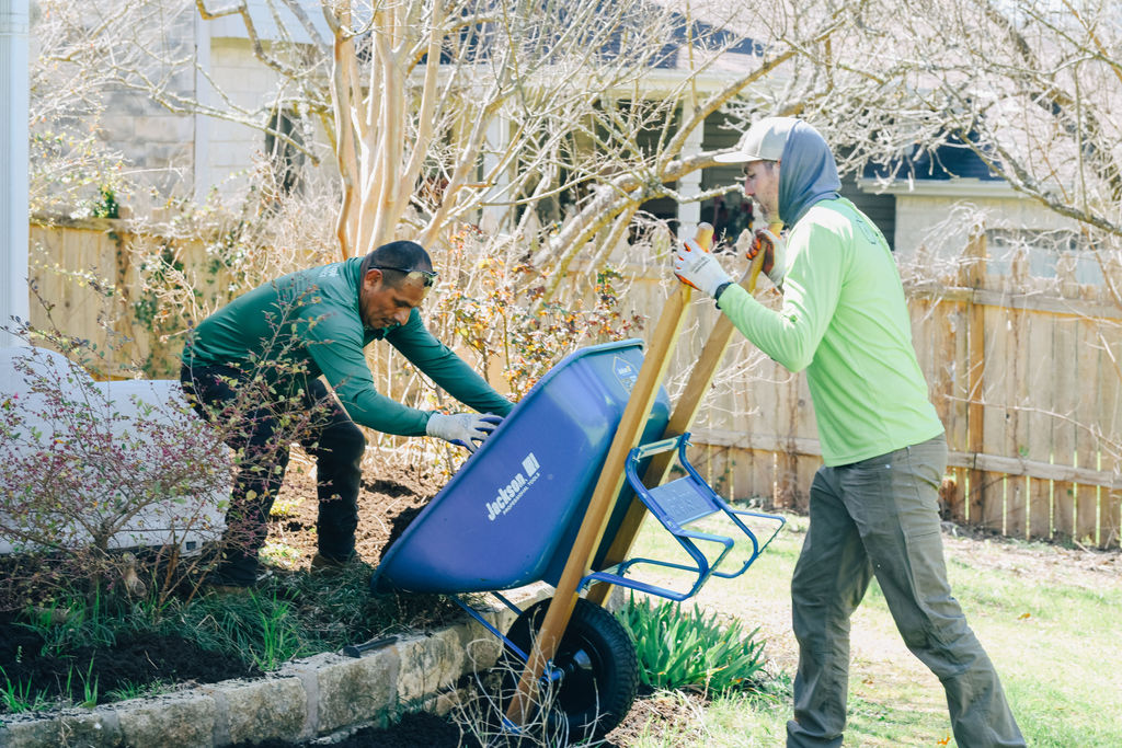 Adam's Apple Tree Service crew laying soil with a wheelbarrow in Austin TX